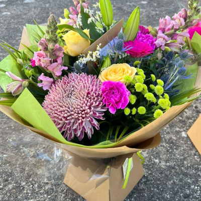 Meadow Breeze - A cheerful mix of seasonal blooms in pink, lilac, lemon yellow, and lavender hues. Features chrysanthemums, carnations, lisianthus and more.