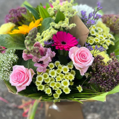Spring Charm - Bursting with charm, this design blends pink roses, yellow sunflowers, gerbera, snapdragons and daisies in a rustic kraft wrap. A seasonal favourite.